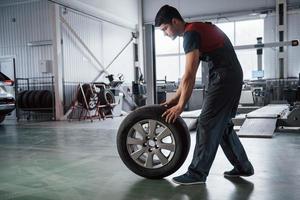 Gorgeous shadows. Mechanic holding a tire at the repair garage. Replacement of winter and summer tires photo