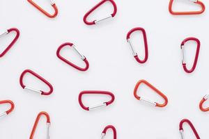 Trust and safety conception. Many of the red colored carabiners on lying on the white table photo