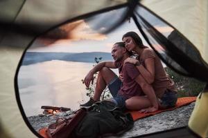 View from tent of couple lying a view of lake during hiking trip. avel Lifestyle concept adventure vacations outdoor photo