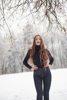 Hot modern woman. Pretty girl with long hair and in black blouse is in the winter forest photo