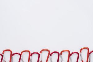 Designer's view. Many of the red colored carabiners on lying on the white table photo