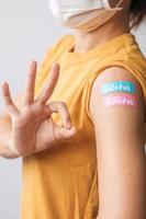 woman showing OK sign with bandage after receiving covid 19 vaccine. Vaccination, herd immunity, side effect, booster dose, vaccine passport and Coronavirus pandemic photo