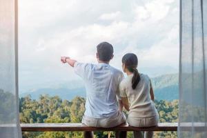 Couple tourist relaxing and looking mountain view at countryside home or homestay in the morning. Vacation, together travel, honeymoon, blogger, journey, trip and relaxing concept photo