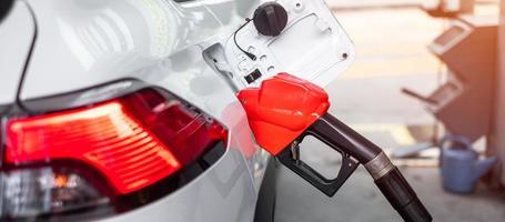 refuel to car, gasoline fuel nozzle in vehicle at petrol station. Oil Price, petroleum economy, inflation and commodity concept photo