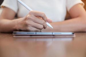 woman using tablet for sms messages, hand holding pencil typing touchscreen mobile phone in cafe or modern office. lifestyle, technology, Social media and network concept photo