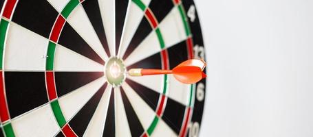 Red dart hitting a target on center of Bullseye or Dartboard. Business, competition, goal, success and marketing concept photo