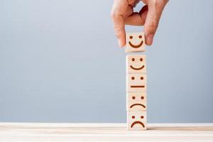 Hand holding smile face symbol on wooden cube blocks. Emotion, Service rating, ranking, customer review, satisfaction and feedback concept photo