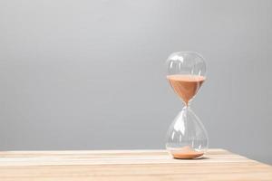 Hourglass on table office with copy space, Sand flowing through the bulb of Sandglass measuring the passing time. countdown, deadline, Life time and Retirement concept photo