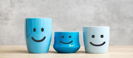 día mundial de la sonrisa y concepto del día internacional del café. cara feliz de la taza de café azul para la revisión del cliente. calificación del servicio, clasificación, satisfacción y retroalimentación foto