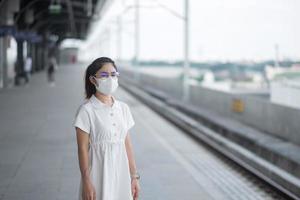 woman wearing Protective face mask prevention coronavirus and PM 2.5 pollution during waiting train. public transportation. safety under covid-19 pandemic and dust photo