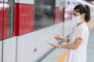 woman clean hand by alcohol gel sanitizer in train or public transportation, protection Coronavirus disease infection. Personal hygiene, safety and travel transport under COVID-19 concepts photo