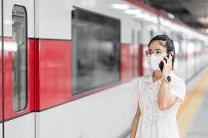 woman using smartphone during wearing protective face mask in train. public transportation, technology and safety under covid-19 pandemic photo