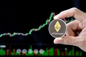 Silver Ethereum cryptocurrency coin with candle graph background, Crypto is Digital Money within the blockchain network, is using technology and online internet exchange. photo