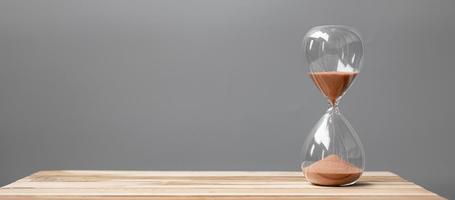 Hourglass on table office with copy space, Sand flowing through the bulb of Sandglass measuring the passing time. countdown, deadline, Life time and Retirement concept photo