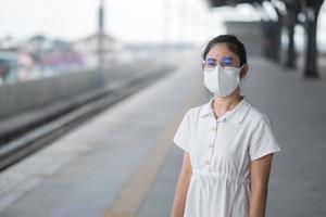 woman wearing Protective face mask prevention coronavirus and PM 2.5 pollution during waiting train. public transportation. safety under covid-19 pandemic and dust photo