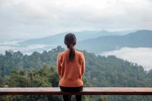 Happy woman relaxing and looking mountain view at countryside home or homestay in the morning. Vacation, blogger, SoloTravel, journey, trip and relaxing concept photo
