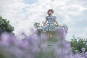 Happy woman tourist in blue dress enjoy in purple Margaret flowers garden. travel, nature, vacation and holiday concept photo