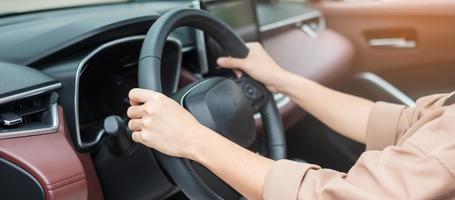 woman driver driving a car on the road, hand controlling steering wheel in electric modern automobile. Journey, trip and safety Transportation concepts photo