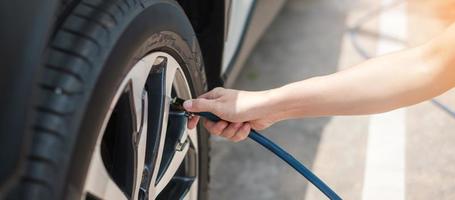 inflando a mano los neumáticos del vehículo, comprobando la presión del aire y llenando el aire en la rueda del coche en la gasolinera. concepto de transporte de autoservicio, mantenimiento y seguridad foto