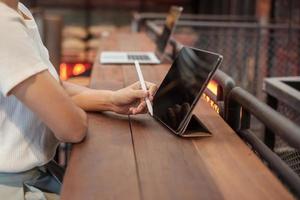 woman using tablet for sms messages, hand holding pencil typing touchscreen mobile phone in cafe or modern office. lifestyle, technology, Social media and network concept photo