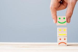 Hand holding smile face symbol on wooden cube blocks. Emotion, Service rating, ranking, customer review, satisfaction and feedback concept photo