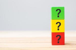 hand holding Questions Mark on wooden cube block on table background. FAQ, Answer, Q and A, Information, Communication and interrogation Concepts photo