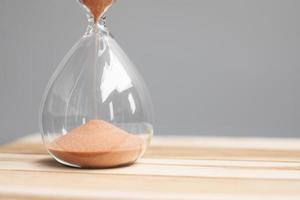 Hourglass on table office with copy space, Sand flowing through the bulb of Sandglass measuring the passing time. countdown, deadline, Life time and Retirement concept photo