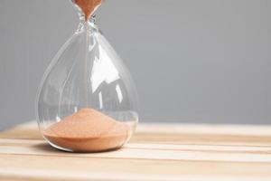 reloj de arena en la oficina de mesa con espacio para copiar, arena que fluye a través de la bombilla de reloj de arena que mide el tiempo que pasa. cuenta regresiva, fecha límite, tiempo de vida y concepto de jubilación foto