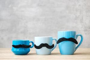 Blue coffee cup and tea mug with Black mustache decor on wood table background in the morning. Blue November, Happy Father day and International men day concept photo