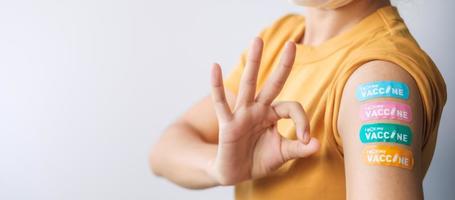 woman showing OK sign with bandage after receiving covid 19 vaccine. Vaccination, herd immunity, side effect, booster dose, vaccine passport and Coronavirus pandemic photo