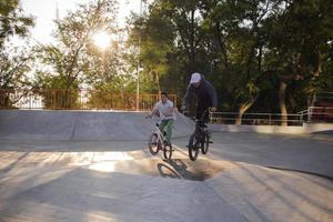grupo de jóvenes con bicicletas bmx en skate plaza, ciclistas acrobáticos en skatepark foto
