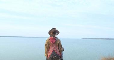 jovem viajante de mulher hipster de chapéu e poncho caminhando ao ar livre nas montanhas perto do lago