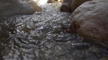 close-up van water dat in slow motion in een borrelende beek door rotsen stroomt video