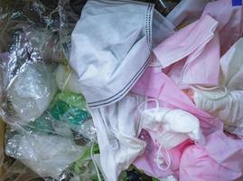 Used sanitary napkins, surgical face mask, and plastic in the trash. Infectious waste management concept. Waste separation. Unhygienic garbage trash. Disgusting trash bin with dirty infectious waste. photo