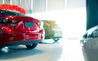 Blurred rear view of red car. Luxury car parked in modern showroom. Car dealership office. Automobile retail shop. Electric and hybrid car business concept. Automobile leasing. Automotive industry. photo