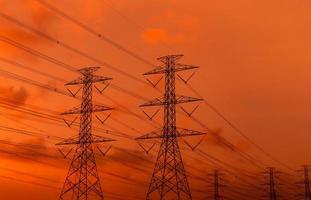 High voltage electric pylon and electrical wire with sunset sky. Electricity poles. Power and energy concept. High voltage grid tower with wire cable. Beautiful red-orange sunset sky. Infrastructure. photo