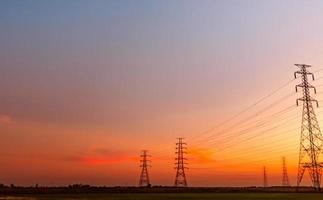 pilón eléctrico de alto voltaje y cable eléctrico con cielo al atardecer. postes de electricidad concepto de potencia y energía. torre de red de alto voltaje con cable de alambre. hermoso paisaje con cielo rojo oad púrpura. foto