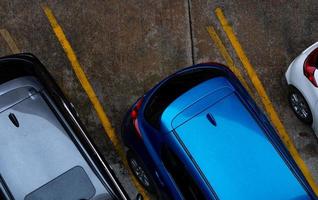 Top view of car parked at concrete car parking lot with yellow line of traffic sign on the street. Above view of car in a row at parking space. No available parking slot. Outside car parking area. photo