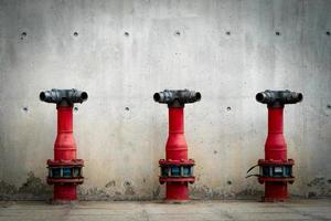 Three fire safety pump on cement floor of concrete building. Deluge system of firefighting system. Plumbing fire protection. Red fire pump in front of concrete wall. High pressure fire safety pump.