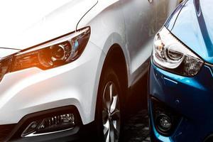 Close up headlamp light of blue and white SUV car parked on concrete parking lot of the hotel or shopping mall. Automotive industry concept. Electric or hybrid car technology. Car rental concept. photo