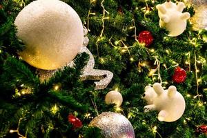 cierra la decoración del árbol de navidad con bolas rojas, doradas, plateadas y blancas, estrella plateada y reno blanco. fondo de navidad. fondo de navidad y feliz año nuevo. bola de colores en el árbol de navidad. foto