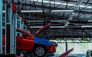 Auto repair shop. Red SUV car is lift in garage for repair and maintenance service. Auto service with lifted vehicle. Car body lifted in workshop for inspection. Car check up at service station. photo