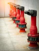Fire safety pump on cement floor of concrete building. Deluge system of firefighting system. Plumbing fire protection. Red fire pump in front of concrete wall. High pressure fire safety pump. photo