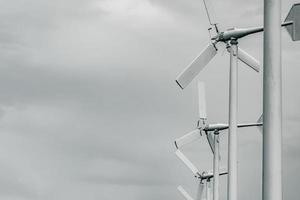 Horizontal axis wind turbine with grey sky and clouds. Wind energy in eco wind farm. Green energy concept. Renewal energy. Alternative electricity source. Sustainable resources. photo