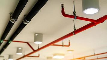 Automatic fire sprinkler safety system and black water cooling supply pipe. Fire Suppression. Fire protection and detector. Fire sprinkler system with red pipes hanging from ceiling inside building. photo