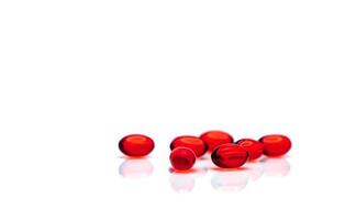 Red soft gel capsule pills isolated on white background. Pile of red soft gelatin capsule. Vitamins and dietary supplements concept. Pharmaceutical industry. Pharmacy drug store. Health care products. photo