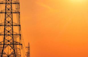 High voltage electric pole and transmission lines in the evening. Electricity pylons at sunset. Power and energy. Energy conservation. High voltage grid tower with wire cable at distribution station. photo