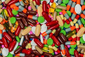 Pile of colorful tablets and capsule pills. Full frame of medicine, vitamins and supplements. Top view many of pills background. Drug, vitamin, supplement and herbal medicine interaction concept. photo