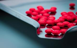 Macro shot detail of red round sugar coated tablets pills on stainless steel drug tray. photo