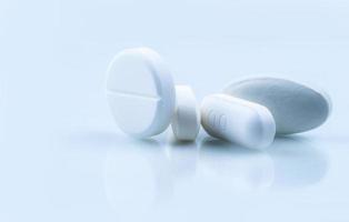 Round and oblong white tablets pills on whit background. Selective focus on white tablets pills. Pharmaceutical industry. Drug production. Pharmacy drugstore products. Pharmaceutical manufacturing. photo